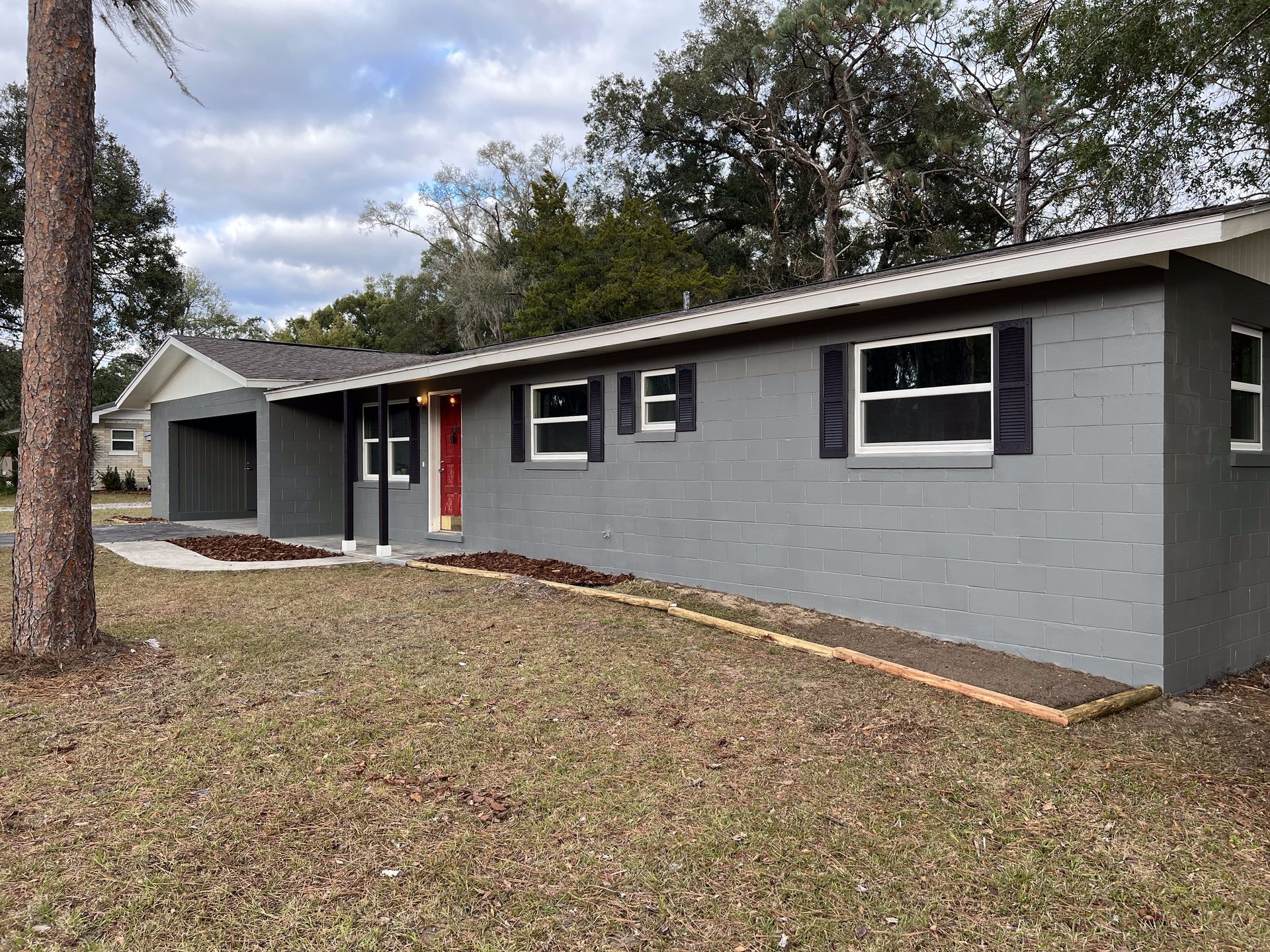 Freshly repainted ranch home exterior with a red front door and matching garage